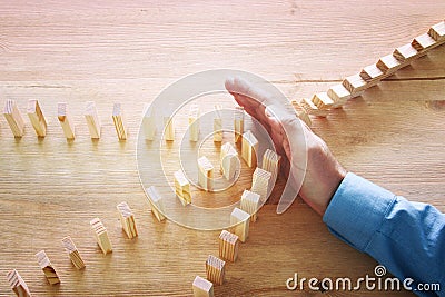 Image of male hand stopping the domino effect. retro style image executive and risk control concept. Stock Photo