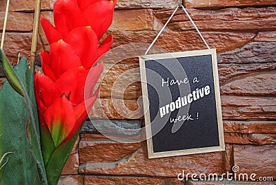 Image of motivational greeting have a productive week on black mini notice board hanged on brick wall besides partly seen Stock Photo