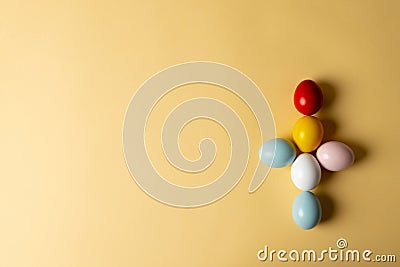 Image of multi coloured easter eggs forming cross with copy space on yellow background Stock Photo