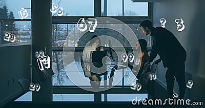 Image of numbers moving over people working late in office using computers Stock Photo