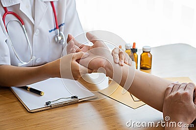 Image of a nurse checking a patient`s pulse. A female doctor shakes hands giving her male patient reassurance and consultation. Stock Photo