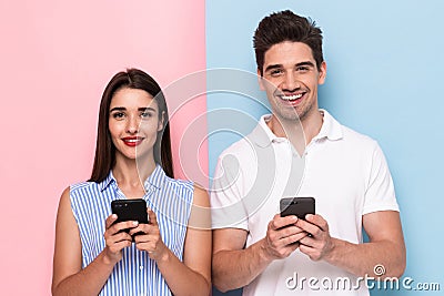 Image of optimistic couple using cell phones together, isolated Stock Photo