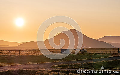 Orange sunset over the mountain with helicopter parked in front of it in Iceland Stock Photo