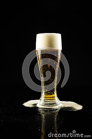 Image of overflowing pint glass of foamy beer, with copy space on black background Stock Photo