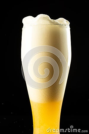 Image of overflowing pint glass of foamy beer, with copy space on black background Stock Photo