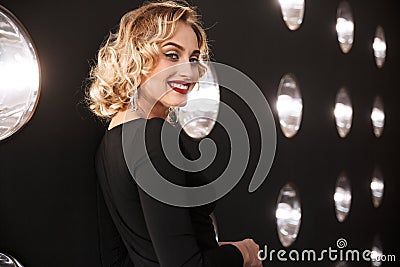 Image of pleased blonde woman wearing elegant dress and jewelry smiling Stock Photo