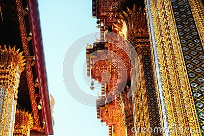 The image portrays a temple in Thailand, adorned with intricate gold and red patterns. Small statues embellish the roof. The photo Stock Photo