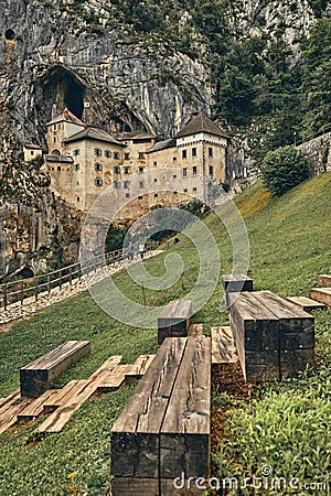 Image of Predjamski castle with benches in the foreground Stock Photo