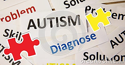 Image of red and yellow puzzle pieces falling over autism text on white background Stock Photo