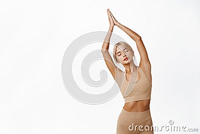 Image of relaxed and peaceful young fitness girl, doing yoga workout, posing in sportsbra against white studio Stock Photo