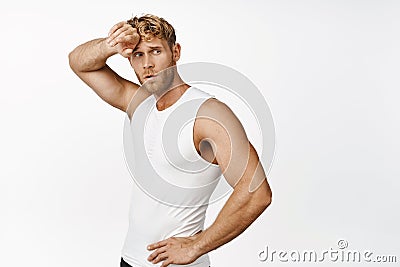 Image of runner, sportsman wipe sweat on forehead and looking around, workout in gym, standing over white background Stock Photo