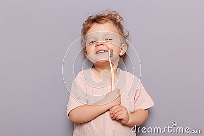 Image of satisfied girl kid holding tooth brush, taking care of her teeth health from early childhood, dental hygiene, blonde Stock Photo