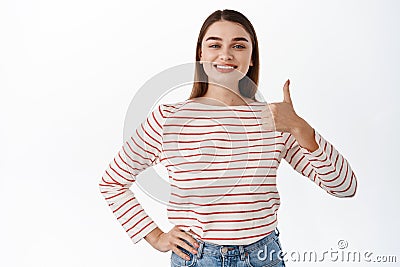 Image of satisfied young female client shows thumbs up in approval, leave positive feedback, pleased with good choice Stock Photo