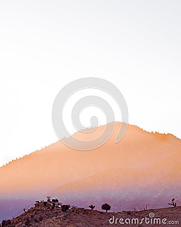 Image showing a mountaintop with sun rays falling diagonal across the horizon over abandoned built up area. Stock Photo
