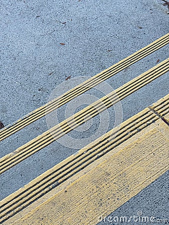 two lines painted in the middle of a sidewalk that is yellow Stock Photo