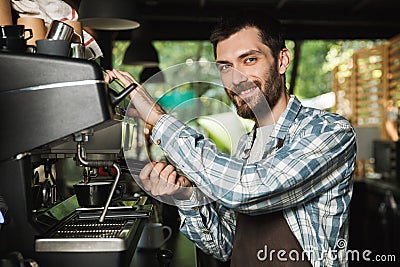 Image of smiling barista man making coffee while working in cafe or coffeehouse outdoor Stock Photo