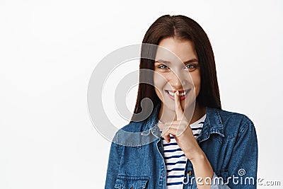 Image of smiling cunning woman tell secret and hush at you, press finger to lips hiding smth, has surprise, tell to be Stock Photo