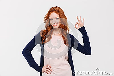 Smiling pretty young redhead lady showing okay gesture. Stock Photo