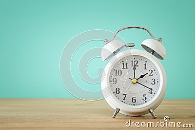 Image of spring Time Change. Summer back concept. Vintage alarm Clock over wooden table. Stock Photo