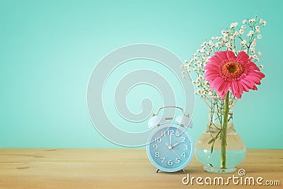 Image of spring Time Change. Summer back concept. Vintage alarm Clock over wooden table. Stock Photo