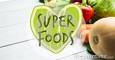 Image of superfoods text in green on green heart, over fresh vegetables on white boards Stock Photo