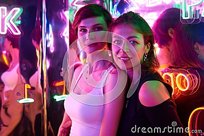 Image of two beautiful women in an amusement park in a room with neon light. Entertainment concept Stock Photo