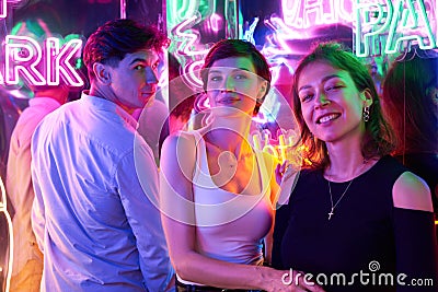 Image of two beautiful women and one man in an amusement park in a room with neon light. Entertainment concept Stock Photo