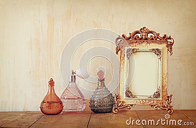 Image of victorian vintage antique classical frame and perfume bottles on wooden table. filtered image Stock Photo