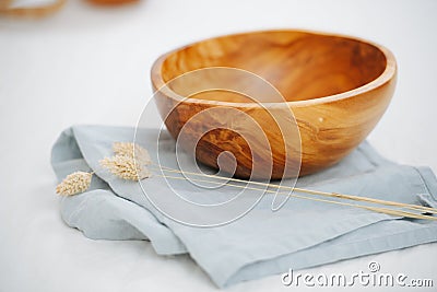 Image of a wooden bowl, standing on a napkin on a white surface Stock Photo