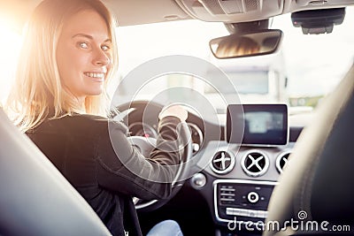 Image of young blonde looking at camera while sitting at wheel of car. Stock Photo