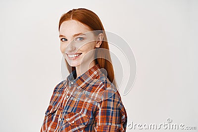 Image of young happy redhead woman with pale skin and no make-up, smiling at camera, standing over white background Stock Photo