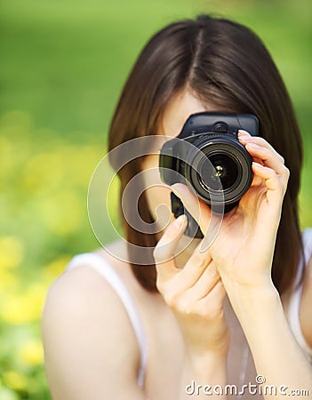 Image of young woman photographing in summer park Stock Photo