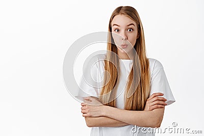 Image of young woman in t-shirt, cross arms on chest and looks surprised, say wow, stare with curious and excited face Stock Photo