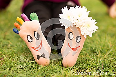 Images of lovely groom and bride just married painted in bright colors on feet of child outdoor at summer Stock Photo