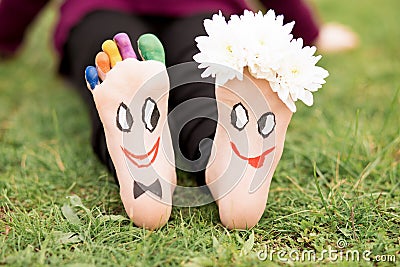 Images of lovely groom and bride just married painted in bright colors on feet of child outdoor at summer. Stock Photo