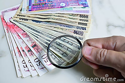 Images of various currencies. Magnifying glass at the US dollar, saving money concept Editorial Stock Photo