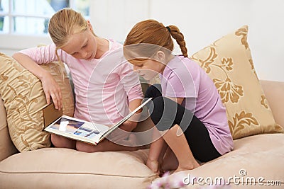 Imagination time. Two sisters reading a storybook in the lounge. Stock Photo
