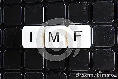 IMF title text word crossword. Alphabet letter blocks game texture background. White alphabetical letters on black Stock Photo