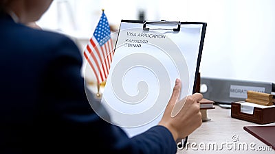 Immigration officer approving visa application, american flag on table, tourism Stock Photo