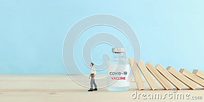 immunity concept. falling wooden cubes stoped by covid-19 vaccine vial. blocking the coronavirus domino effect Stock Photo