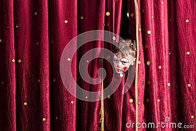 Impatient young actor peeking out from the curtain Stock Photo