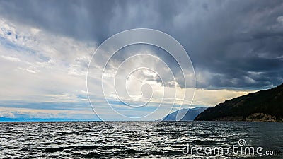 An impending thunderstorm. Clouds over the lake. clouds over the sea. The sun's rays break through the clouds over the lake. Stock Photo
