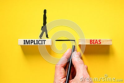 Implicit bias symbol. Concept words Implicit bias on wooden block. Beautiful yellow table yellow background. Businessman hand. Stock Photo