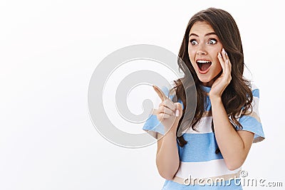 Impressed excited young woman check out awesome promo, see cool product, pointing left stare copy space astonished and Stock Photo