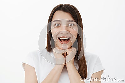 Impressed and overwhelmed cute brunette in white t-shirt listening carefully about amazing event smiling delighted Stock Photo