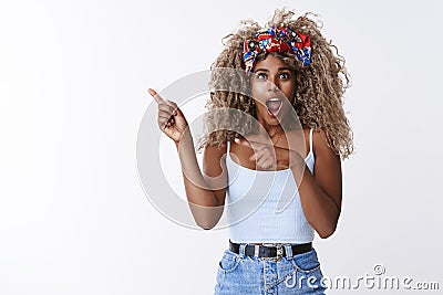 Impressed, stunned african-american curly-haired blond female with stylish hipster headband, open mouth gasping amazed Stock Photo