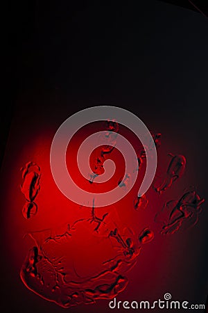 The imprint of the palm of human hand on glass on red background, in dark. Symvol reflection Stock Photo