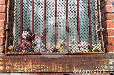 Imprisoned soft toys behind window bars Stock Photo