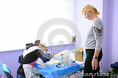 Improving motor control. Woman therapist teaching disabled girl of painting. Municipal Department of rehabilitation. Editorial Stock Photo