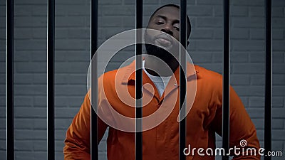 Impudent black prisoner in cell looking directly to camera, dangerous criminal Stock Photo